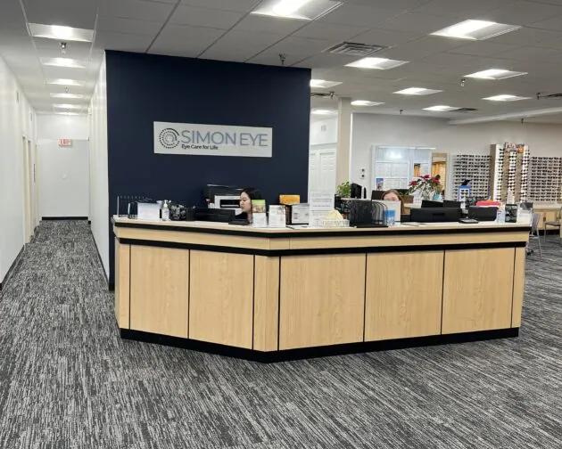 Front desk of Simon Eye eye care center with a receptionist seated behind a counter.